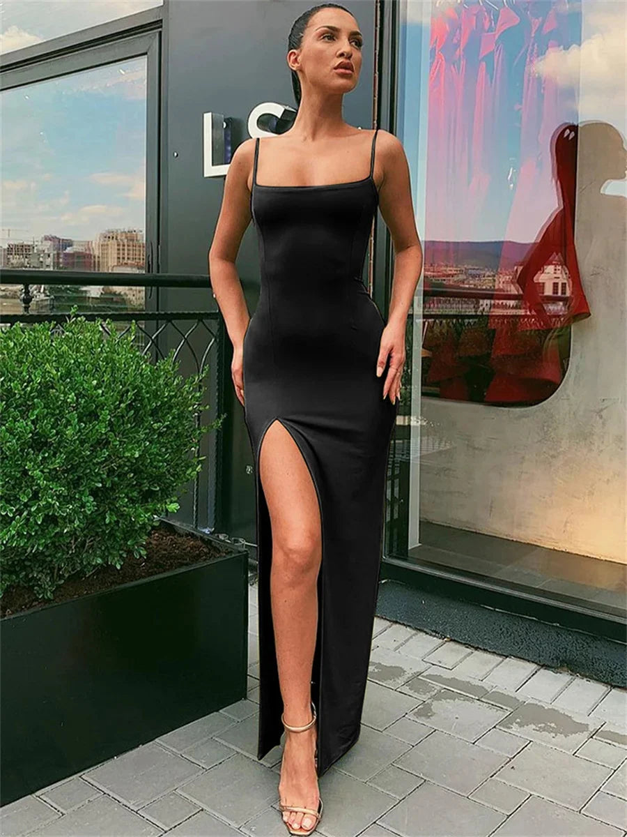 Woman in a black dress with a high slit standing on a rooftop with cityscape background