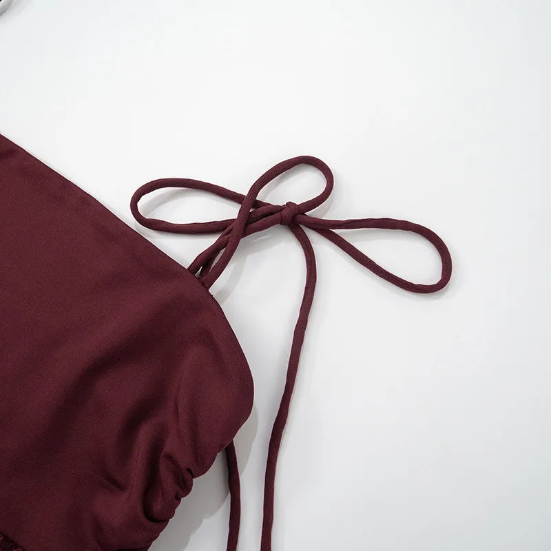 Maroon swimsuit top with a bow on a white background