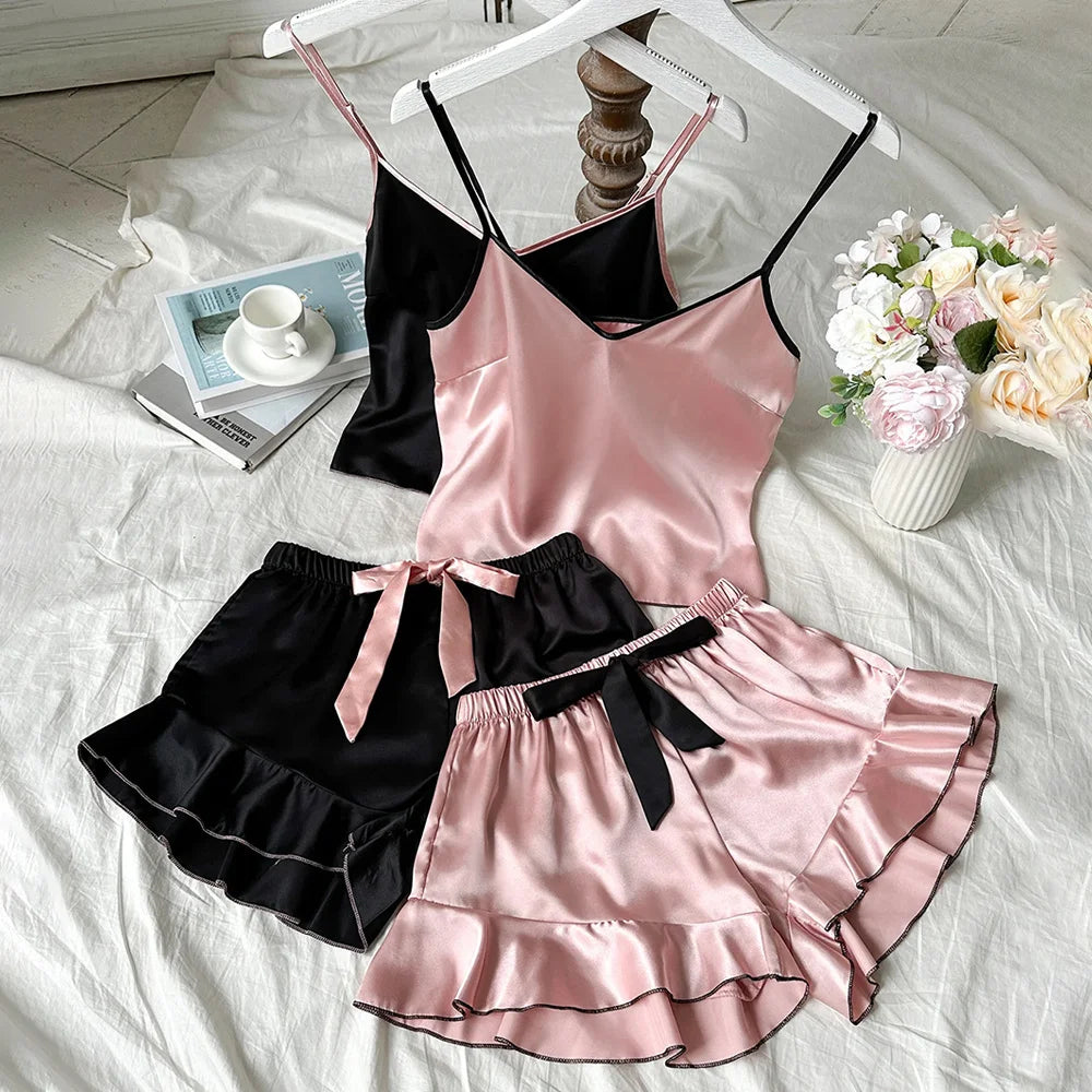 Pink satin nightgown with black lace trim on a white bed with flowers and books.