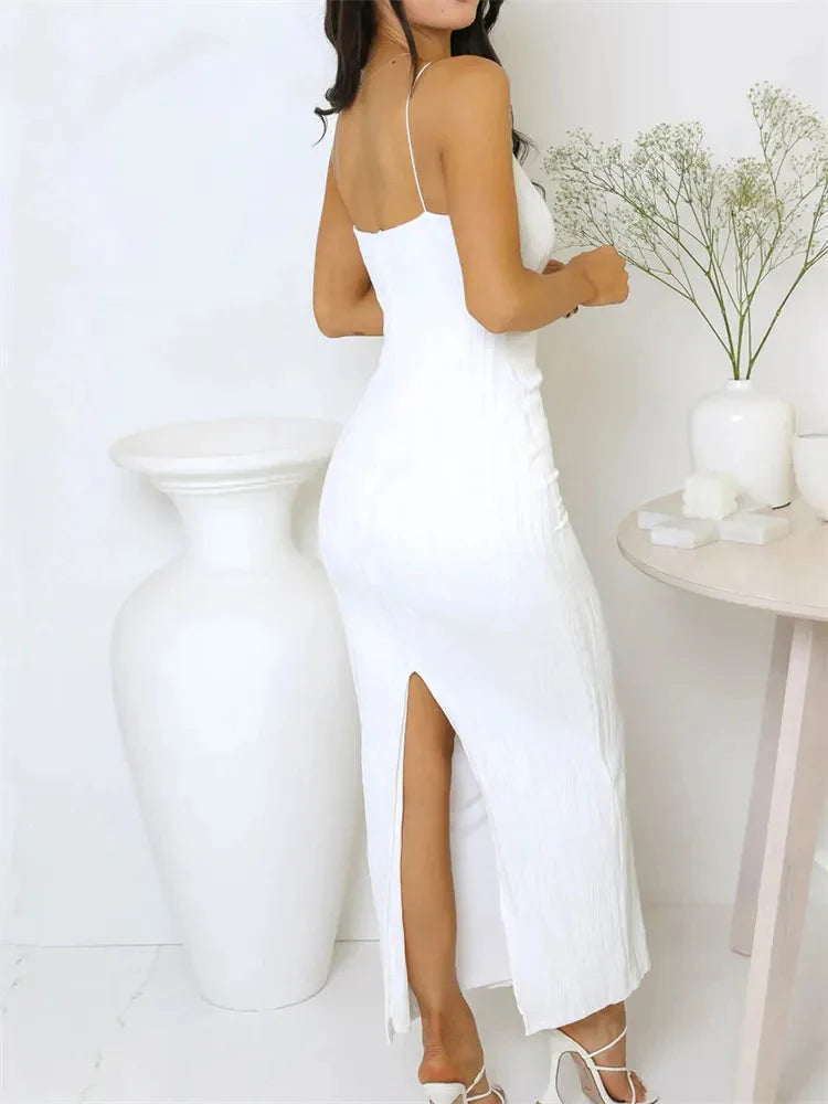 Woman wearing a white dress with a high slit in a minimalistic setting.