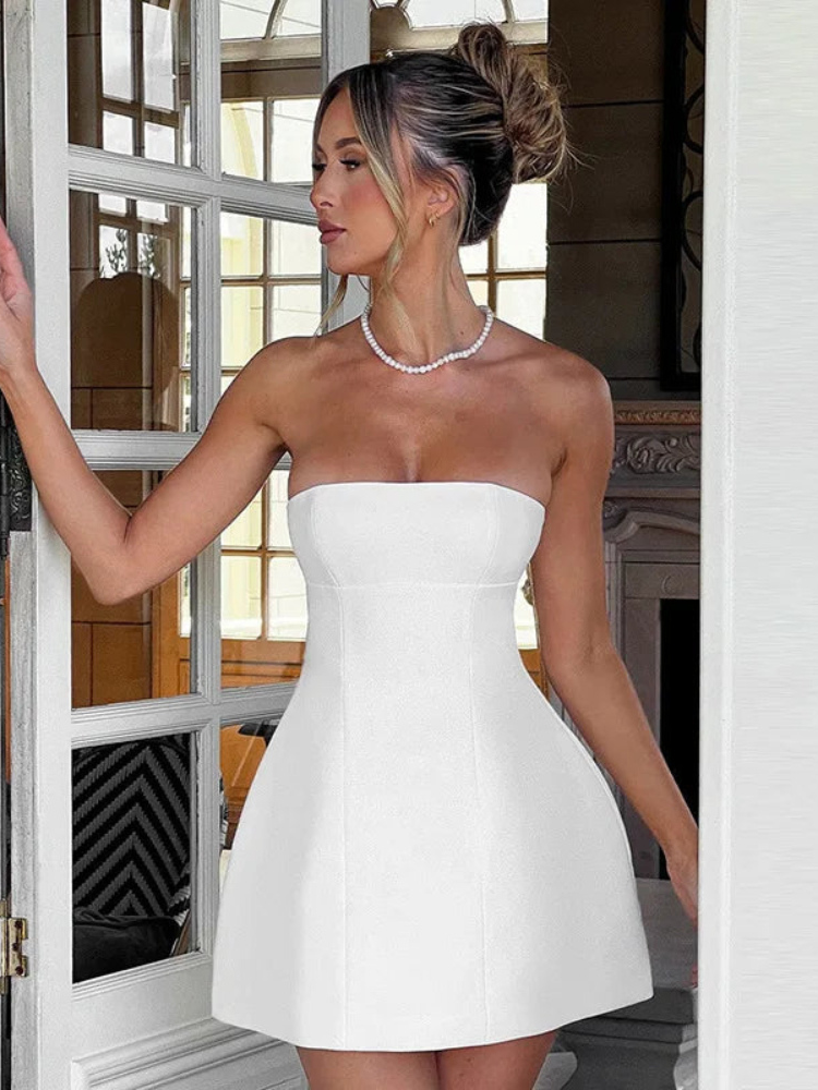 Woman wearing a white strapless dress indoors.