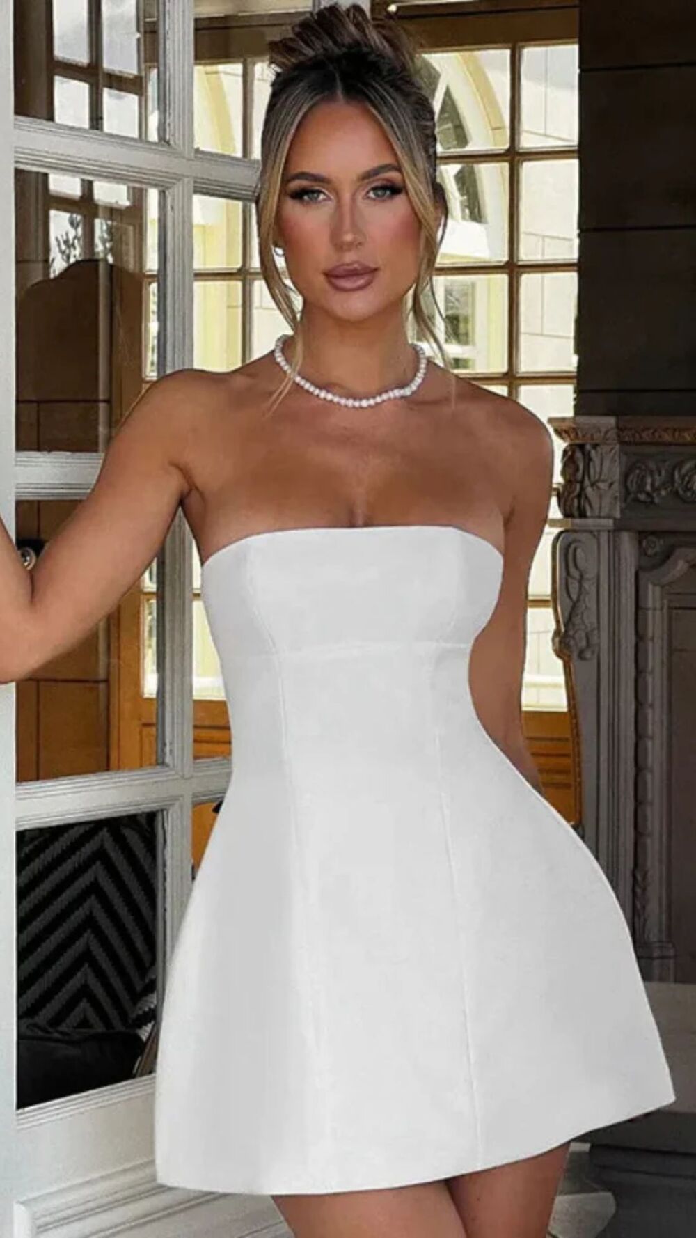 Woman wearing a white strapless dress in an indoor setting